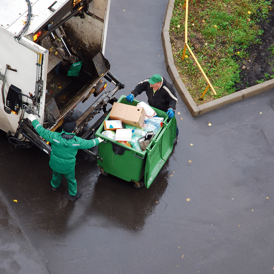 Two people managing waste at a waste collection truck